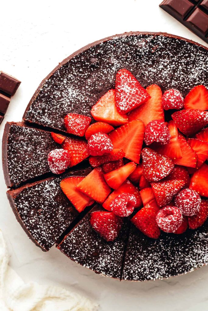 A slice of rich 5-star flourless chocolate cake with glossy ganache on a white plate — naturally gluten-free