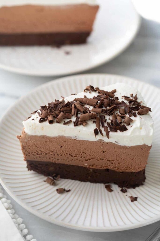 A stunning gluten-free chocolate mousse cake with brownie base, rich mousse layer, whipped cream topping, and chocolate shavings